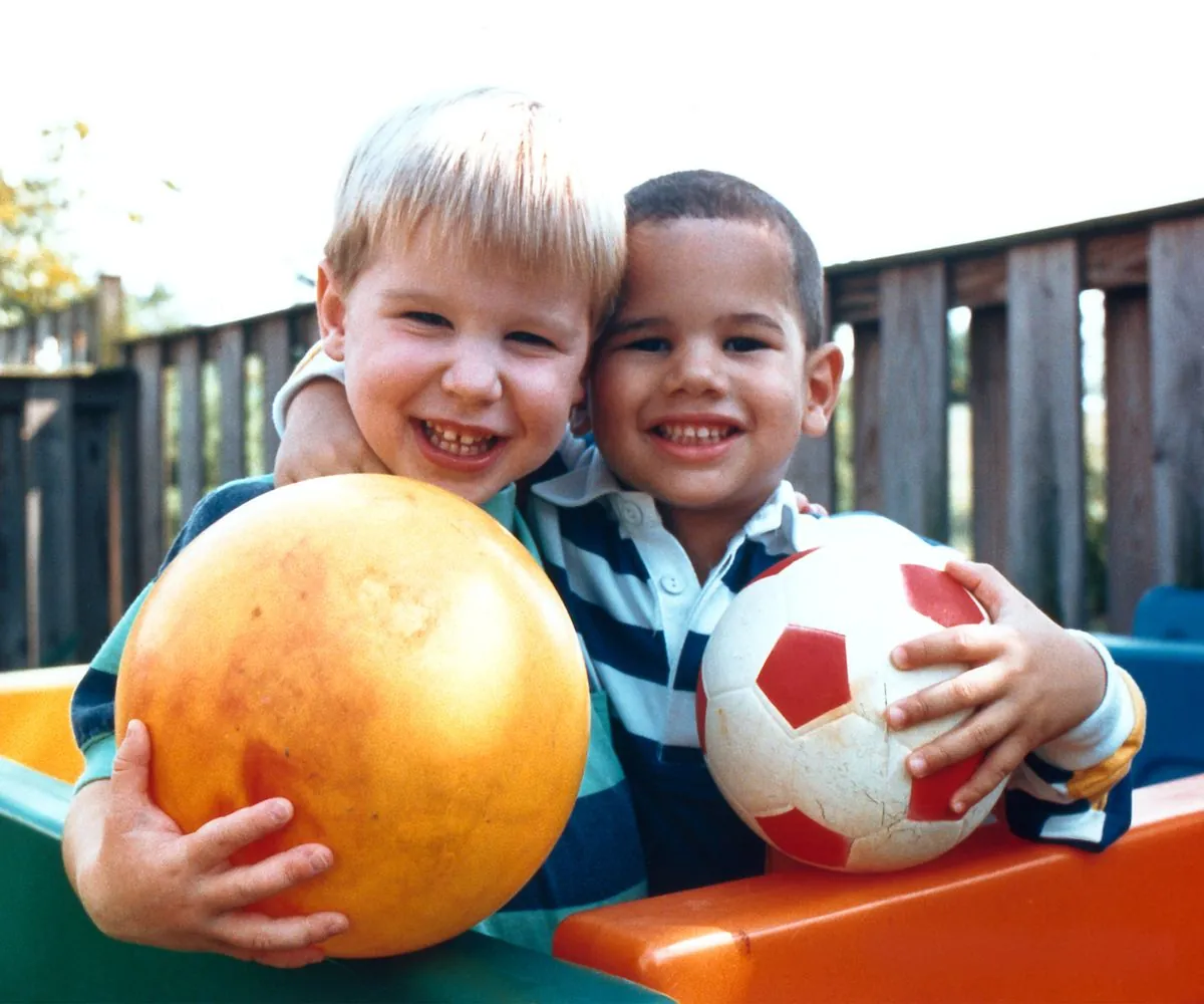 Duas crianças sorrindo com uma bola, como vistas com visão normal